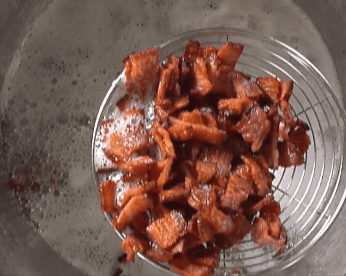 Bacon being drained in a strainer.