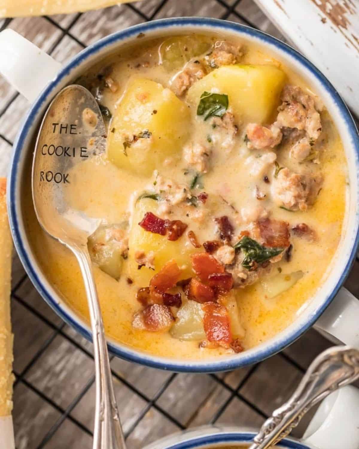 Instant Pot Zuppa Toscana is my new go-to Instant Pot Recipe! Every time we go to Olive Garden I get Zuppa Toscana and I just love that I can make this DELICIOUS copycat recipe at home in under 30 minutes! We first fell in love with this hearty and creamy soup at Olive Garden but I love this quick pressure cooker version even more. This Zuppa Toscana Recipe is loaded with sausage, bacon, potatoes, spinach, and so much flavor. A bowl of Instant Pot Zuppa Toscana with a spoon in it.