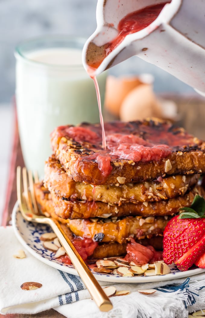 Homemade strawberry syrup being poured over french toast