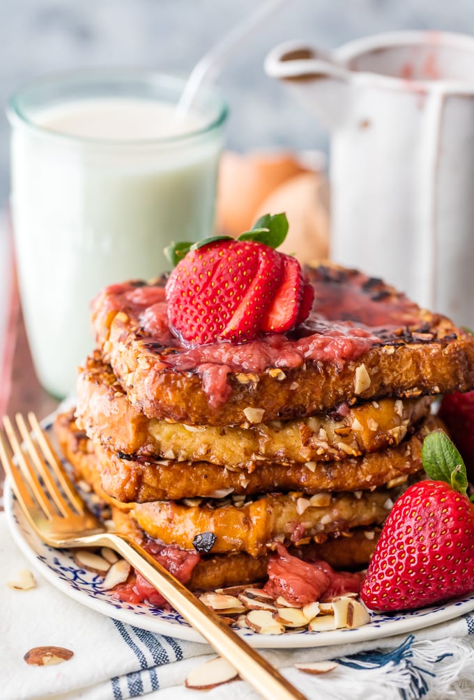 A stack of almond french toast topped with strawberry syrup