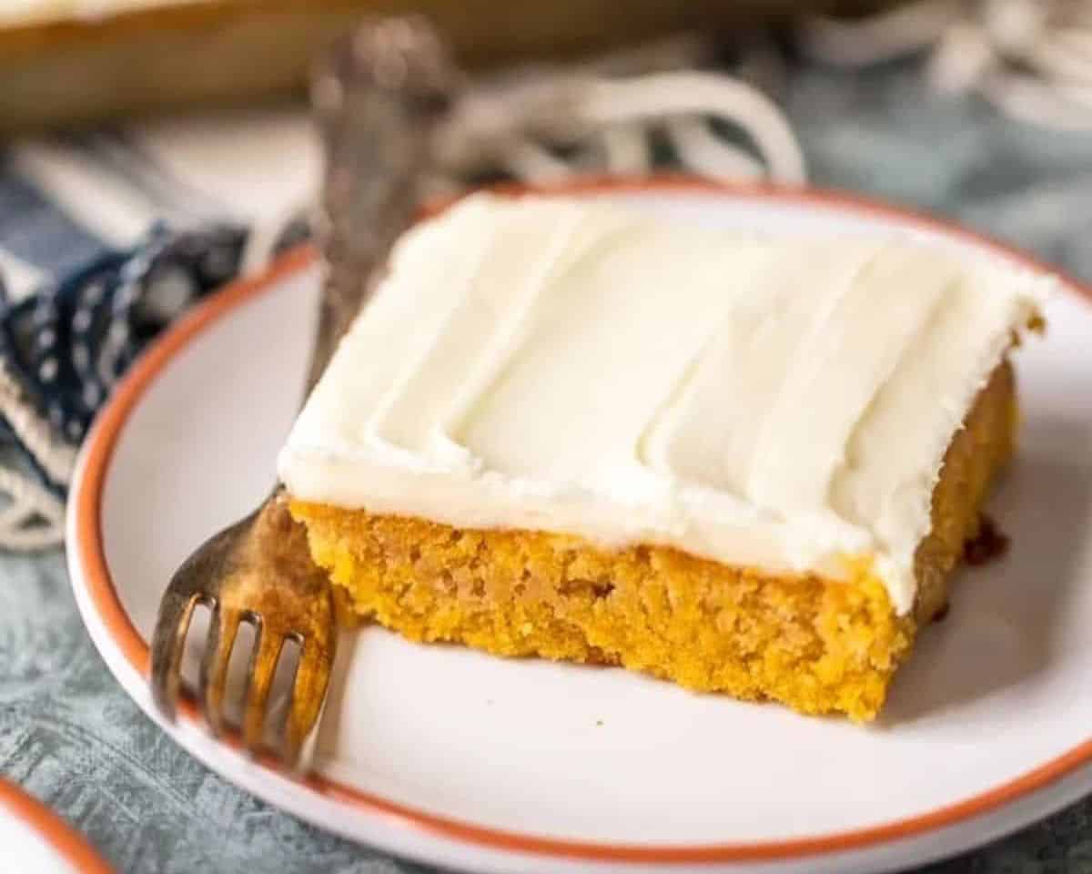 These Gluten Free Carrot Cake Bars are so moist and delicious, thanks to our secret ingredient. You'll never believe how simple and delicious this moist carrot cake recipe is! Try not to eat all the perfect carrot cake frosting before piling it on and serving it to your Easter guests. Best carrot Cake bars ever! carrot cake bar with cream cheese on a plate