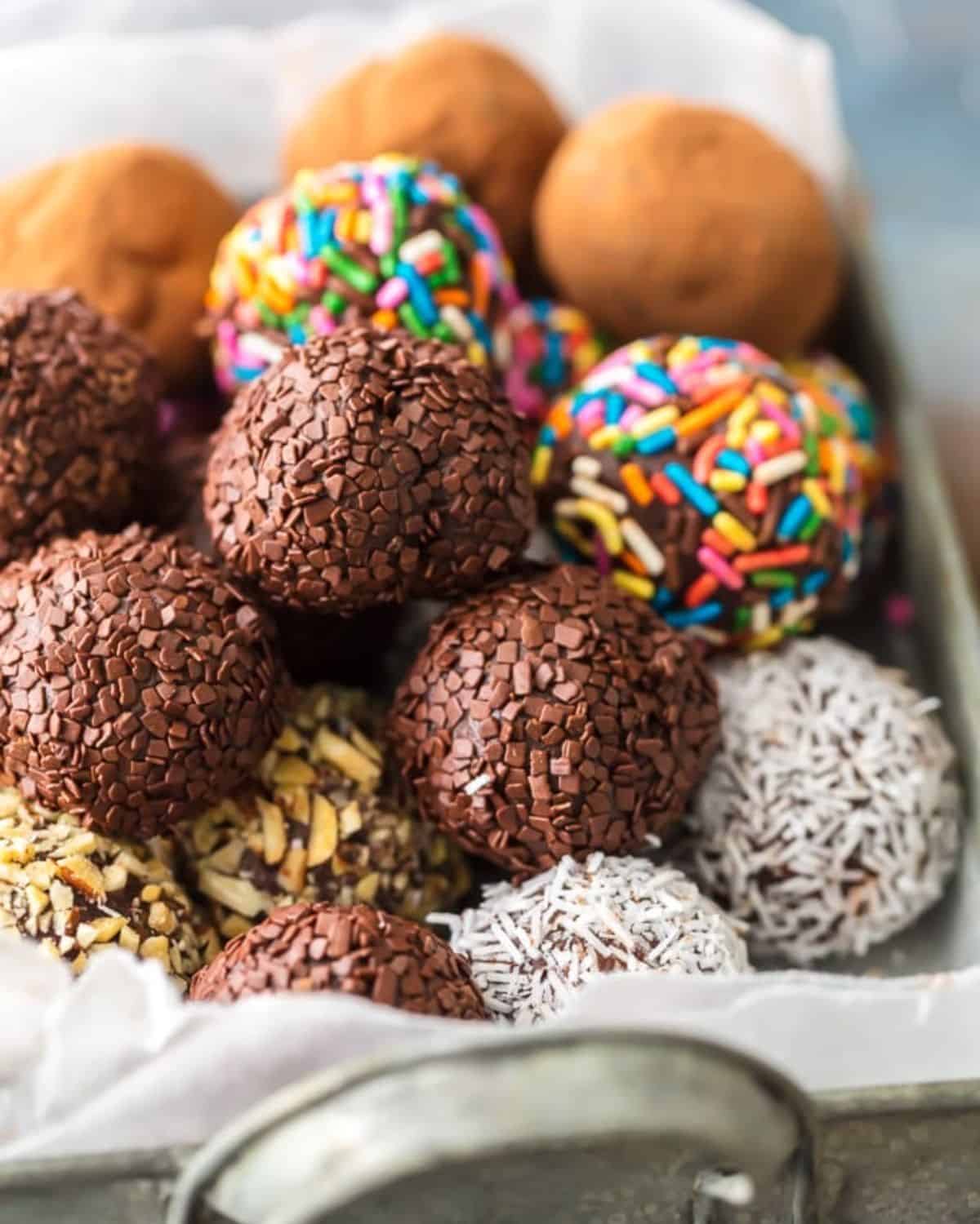 Chocolate Truffles are a must make recipe for any chocolate lover. This Easy Chocolate Truffles Recipe is made with only 5 ingredients and has a unique and amazing flavor. If you've wondered how to make chocolate truffles, this recipe is for you. Softer than fudge, bite-sized, and utterly perfect, you simply can't miss these homemade truffles. Chocolate truffles rolled in chocolate, nuts, coconut, sprinkles, and cocoa powder.