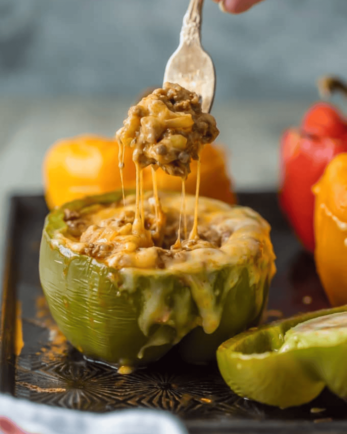 Stuffed Peppers are a delicious dinner or appetizer option. This Mexican Stuffed Peppers recipe is our go-to easy recipe because it's SO good.. These Enchilada Stuffed Peppers with Cheese are loaded with beef, green chiles, onions, enchilada sauce, and so much cheese! You won't believe how easy this stuffed bell pepper recipe is and how much your entire family will love it. A fork pulling out cheesy beef from a stuffed pepper.