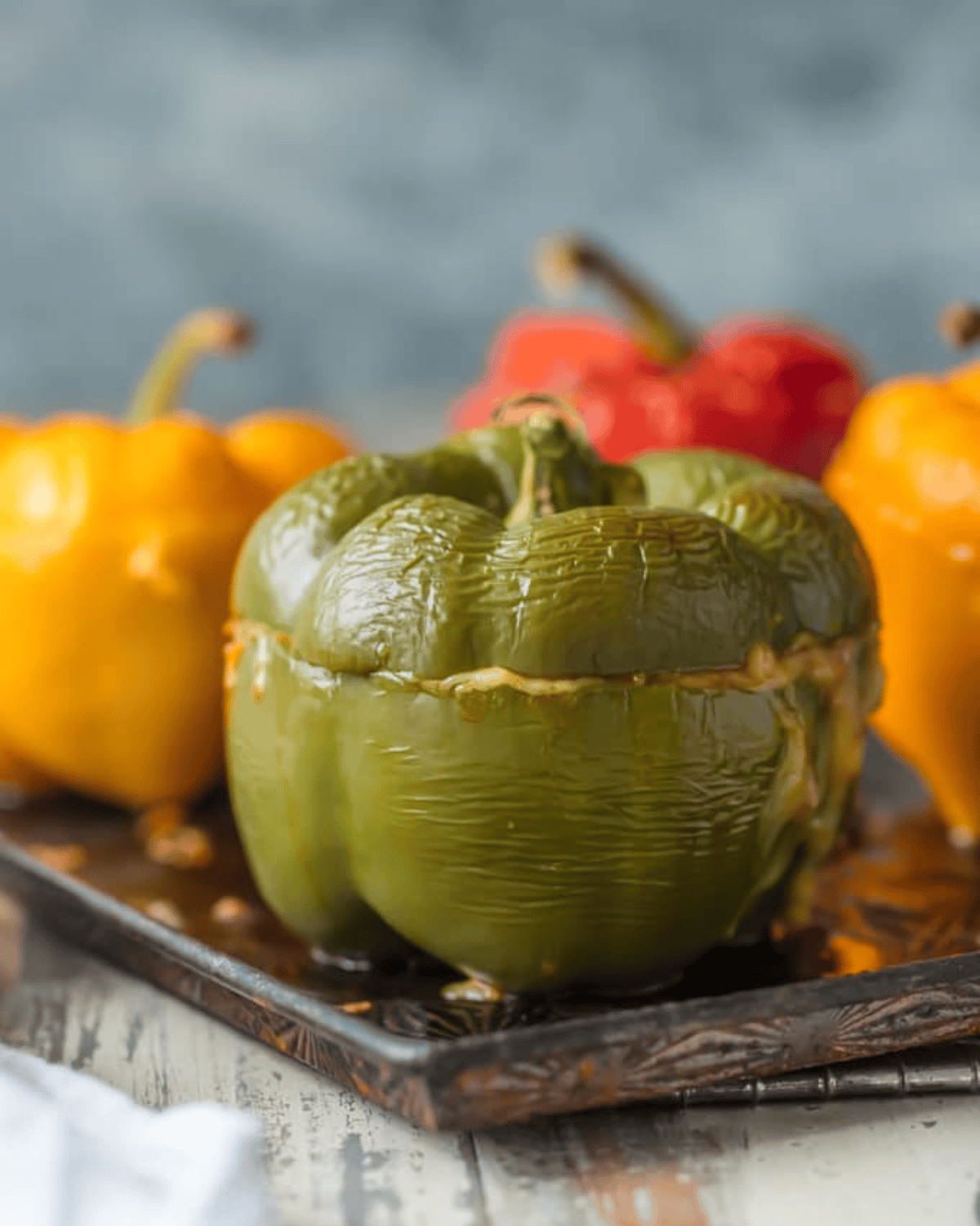 This STUFFED PEPPERS RECIPE is our go-to easy dinner recipe. These Cheesy Enchilada Stuffed Peppers are loaded with beef, green chiles, onions, enchilada sauce, and so much cheese! You won't believe how easy this stuffed bell pepper recipe is and how much your entire family will love it. Cooked stuffed peppers on a baking tray.