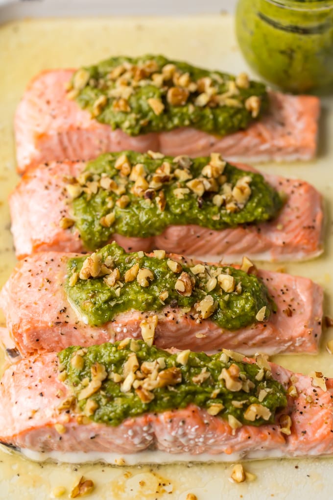 Baked Salmon with Basil Walnut Pesto is our favorite simple yet elegant seafood dinner. This Pesto Salmon Recipe is bursting with flavor and good fat. The tender flakey salmon is basted in butter, white wine, and lemon juice before baking and then topped with an amazing nutty and rich Basil Walnut Pesto. Best Salmon Recipe ever!