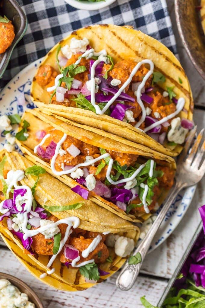 buffalo shrimp tacos on a plate garnished with cilantro and onion