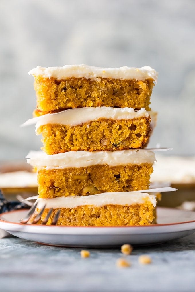 carrot cake bars with cream cheese icing stacked on plate