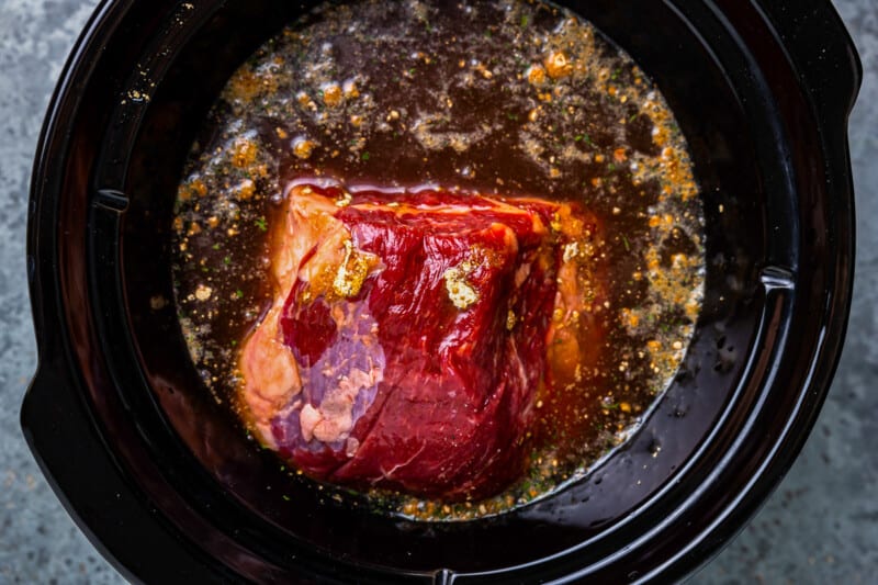 crockpot french dip in a crockpot with broth over it