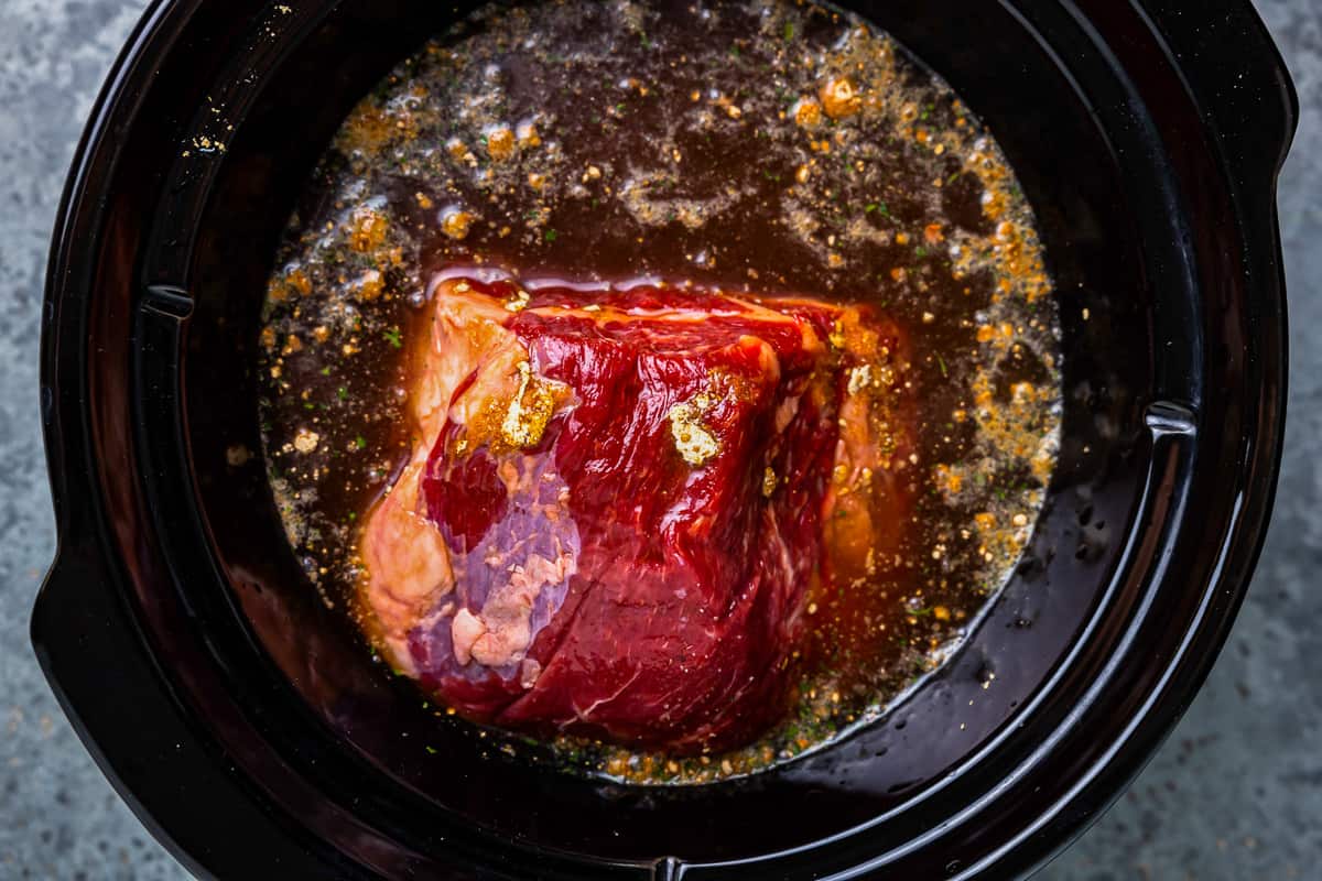 crockpot french dip in a crockpot with broth over it