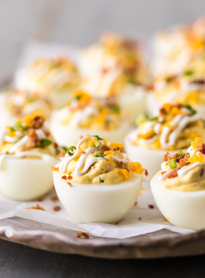 loaded deviled eggs garnished with cheese, sour cream, chives, and bacon