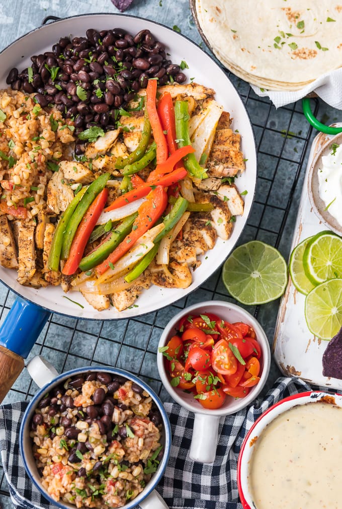 skillet filled with fajitas, surrounded by bowls of ingredients