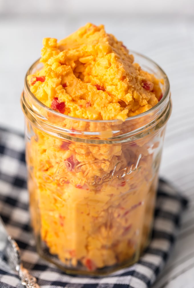 Want to learn How to Make Pimento Cheese? You've come to the right place! This Homemade Pimento Cheese recipe is bold and full of flavor. The classic Southern spread is perfect to serve at parties, and of course it makes an amazing Pimento Cheese Sandwich. With tasty Colby cheese and sweet Pimento peppers, this is the Best Pimento Cheese recipe out there! Pimento cheese in a glass mason jar