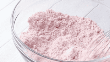 Pink strawberry cake mix powder in a bowl with a whisk.