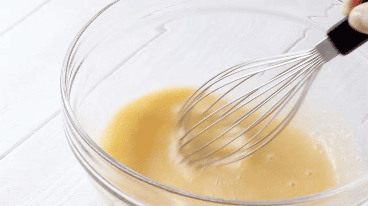 eggs in a glass bowl with a whisk.