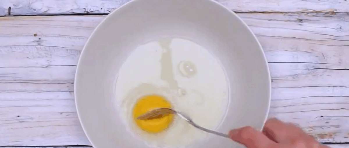 Scrambling the egg in a white bowl. 