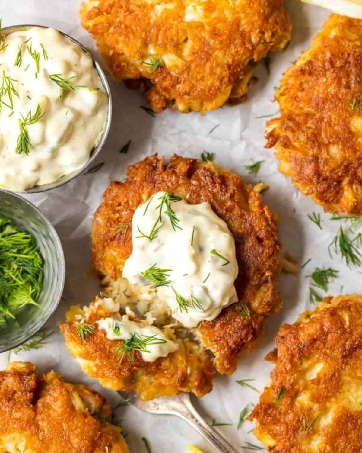 The BEST CRAB CAKE RECIPE is right here in front of you! I loooove fresh, crispy crab cakes, and these Baltimore Crab Cakes are really hitting the spot. This crab cake recipe is my ideal seafood dinner, and once we add on the homemade tartar sauce...YUM! I can't get enough of these things. Crab cakes with tartar sauce on a baking sheet.