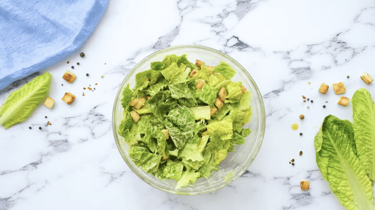 tossed caesar salad in a glass bowl.