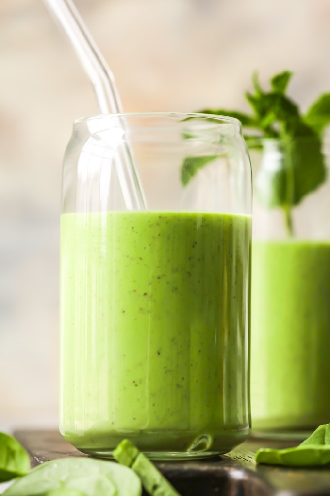 close up of green smoothie in a glass with a glass straw