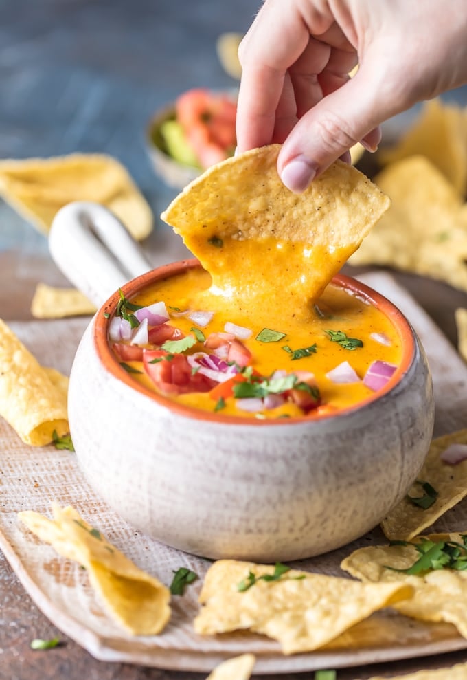 hand dipping tortilla chip in dip