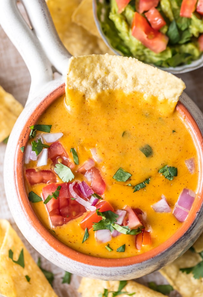 a chip submerged into queso dip