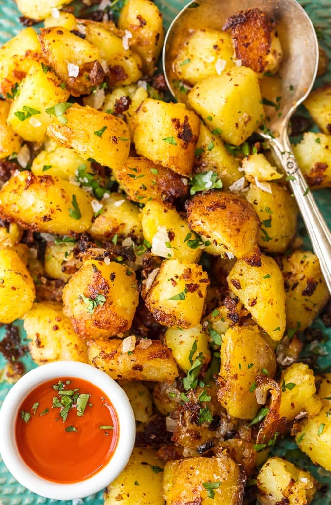 close up on a platter of crispy home fries with a serving spoon