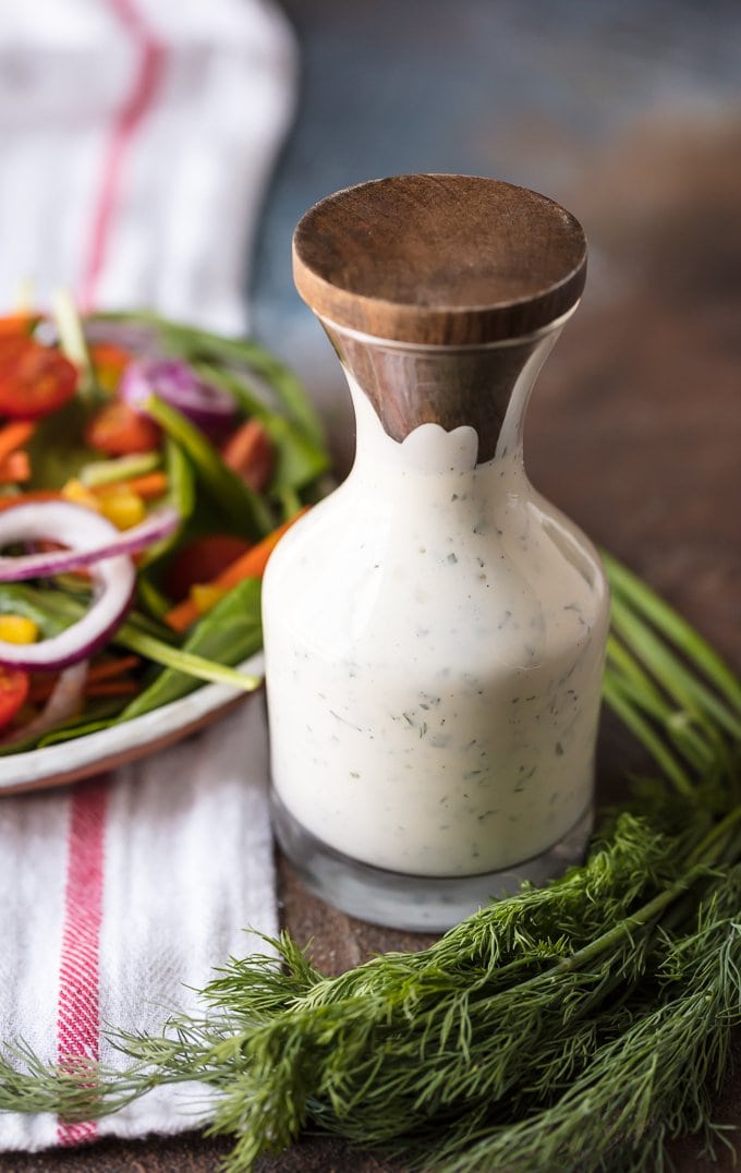 Easy ranch dressing recipe in glass jar, next to a plate of salad