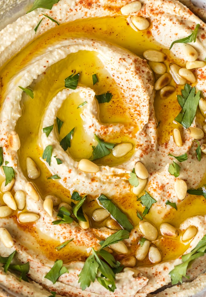 A swirl of hummus and olive oil, sprinkled with pine nuts and red pepper flakes