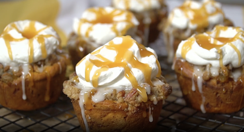 mini apple pies topped with icing, whipped cream, and caramel sauce.