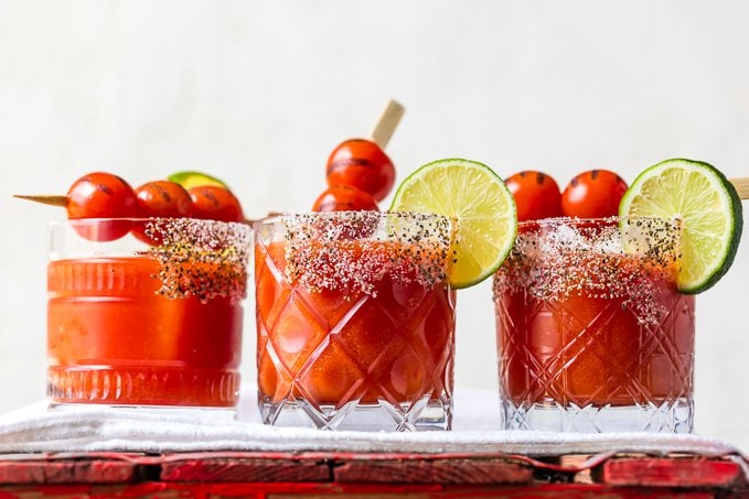 3 short glasses with salt and chili powder rims, filled with tomato margaritas