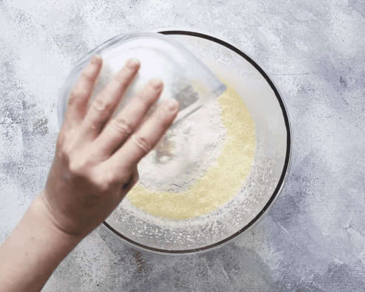 Combining wet and dry ingredients in a glass bowl.