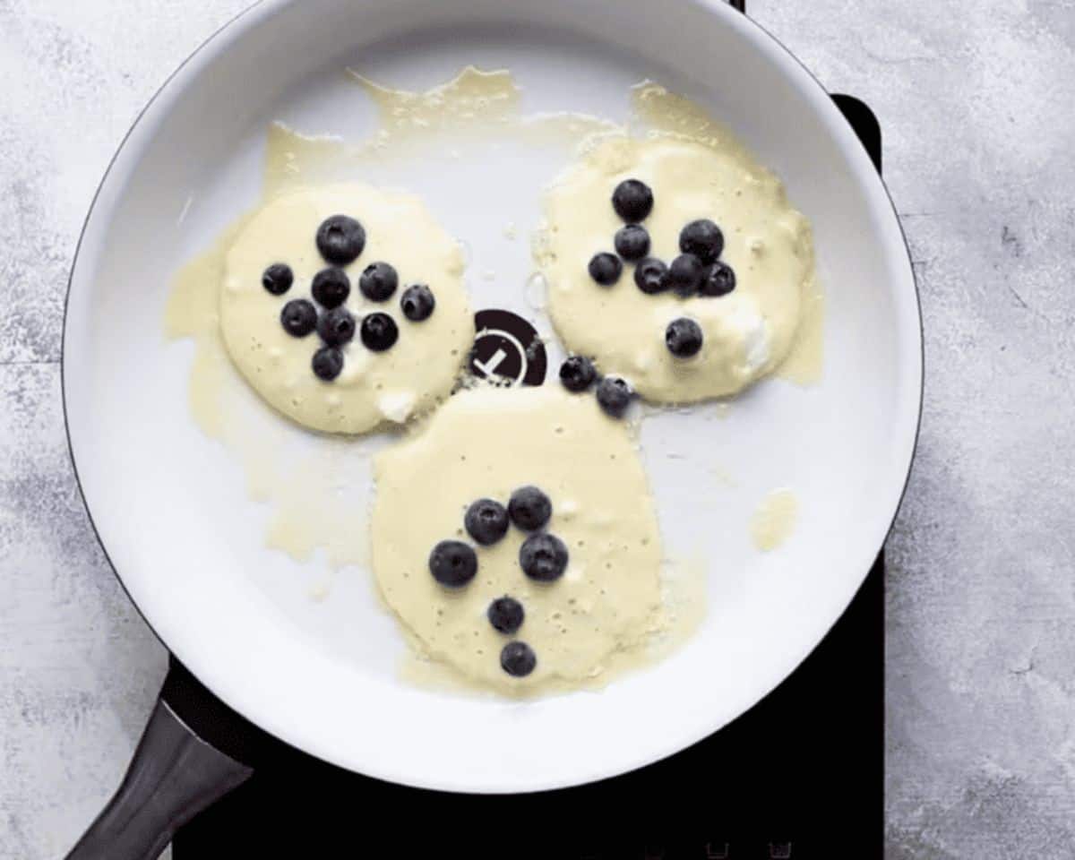 Cooking the pancakes with blueberries sprinkled on top.