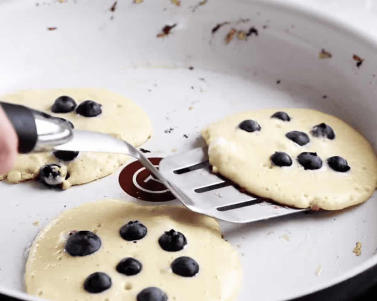 Cooking blueberry pancakes in a griddle.