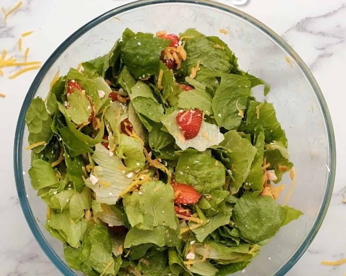 The salad ingredients tossed together in a glass bowl.