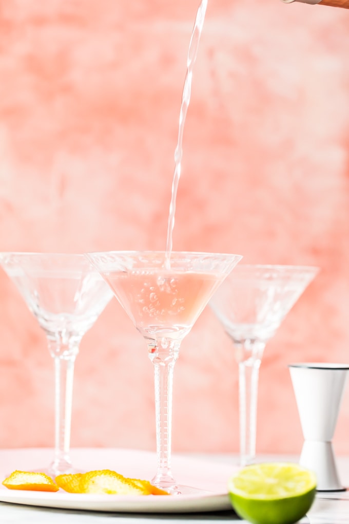 filling cocktail glasses with a cosmopolitan