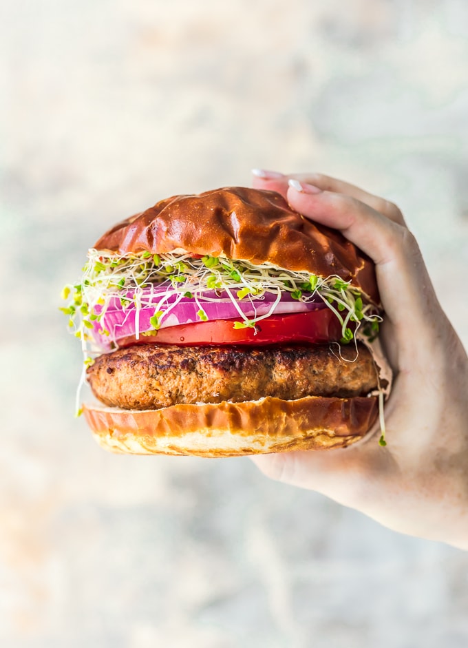 Burgers are one of those foods that EVERYONE should know how to make. I've gathered some of the BEST burger recipes and burger ideas, along with helpful information to help teach you how to cook burgers to perfection. Whether you prefer beef, chicken or turkey burgers, or even veggie burgers, you'll love these homemade burger recipes! a hand holding up a turkey burger