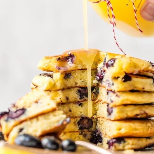 Blueberry Pancakes just might be the most comforting breakfast ever. It's hard not to think of weekend mornings at home with the family when chowing down on pancakes, and that's exactly what this recipe is for! If you want o know how to make blueberry pancakes, it's simple! This is a classic blueberry pancake recipe, light, fluffy, and fruity. And to top it all off, there's a tasty homemade Lemon Sauce to pour on top!