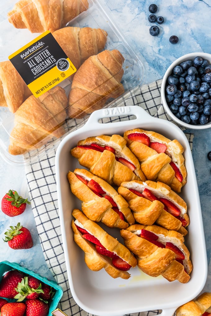Strawberries, blueberries, and croissants around a casserole dish with french toast bake