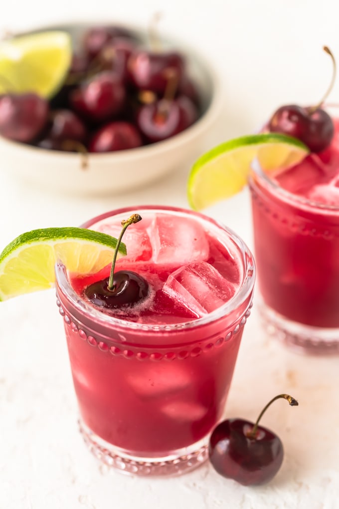 Two cherry limeades next to a bowl of cherries