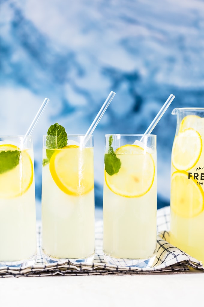 3 glasses filled with freshly squeezed lemonade, lemon slices, and mint