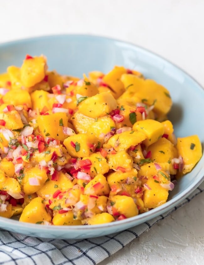 Mango Salsa is a fruity, flavorful spin on traditional salsas. Replacing tomatoes with mango chunks creates something super fresh and fun. This easy mango salsa recipe can be used as a dip with tortillas chips, but it also makes a great topping for tacos, chicken, and more.