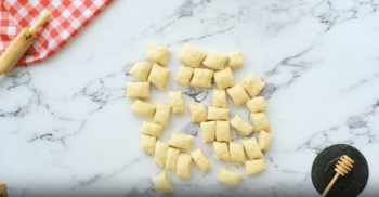 dough cut into bite-sized pieces on a marble counter.