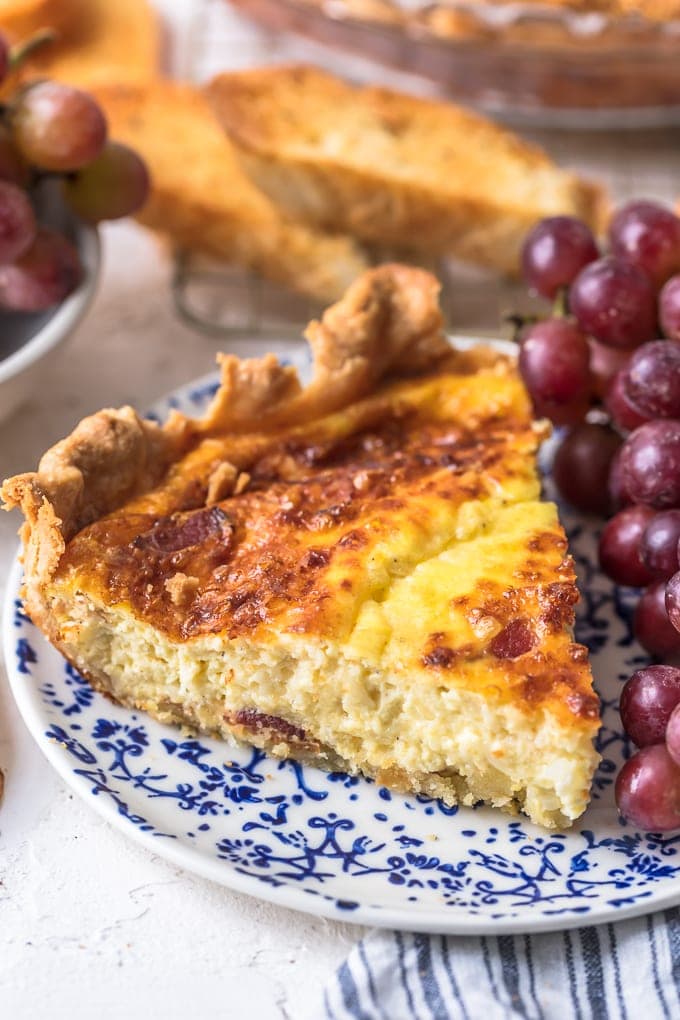 a plate with a slice of quiche and grapes