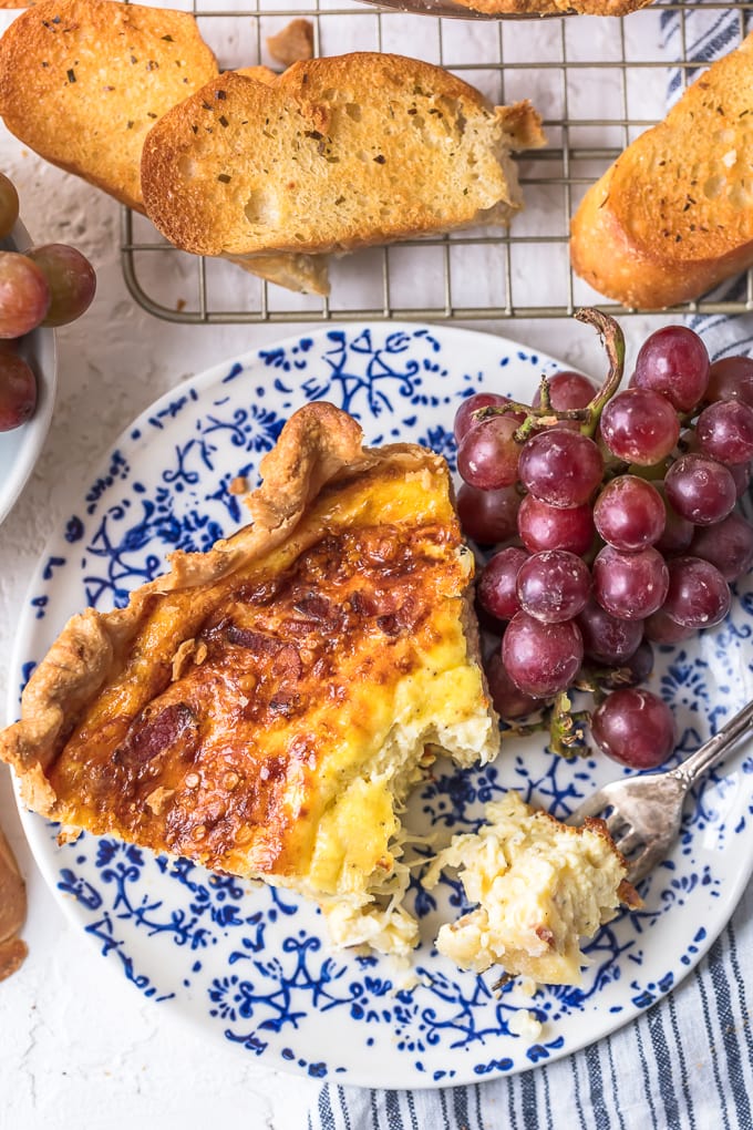 Partially eaten Quiche on a blue and white plate with grapes