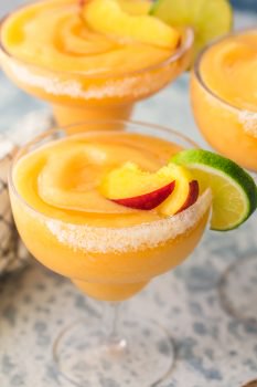 This Skinny Peach Frozen Margarita is Summer in a glass! I love the bright flavor of a delicious Peach Margarita, but lightened up in Skinny Margarita form. This cocktail is made with simple ingredients such as frozen peaches, peach sparkling water, agave nectar, lime juice, and of course, Tequila! There's no better way to celebrate Summer than with these perfect fruity Frozen Margaritas!