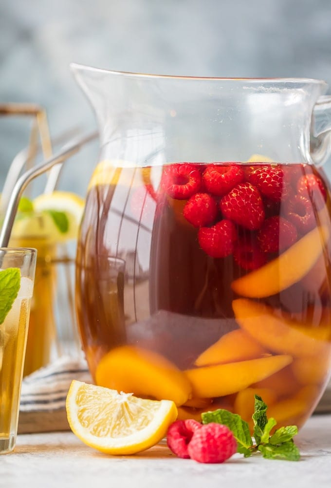 A pitcher of sweet tea sangria filled with raspberries and peaches