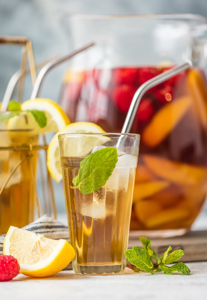 Glass of sangria sitting in front of a pitcher filled with sangria and chopped fruit