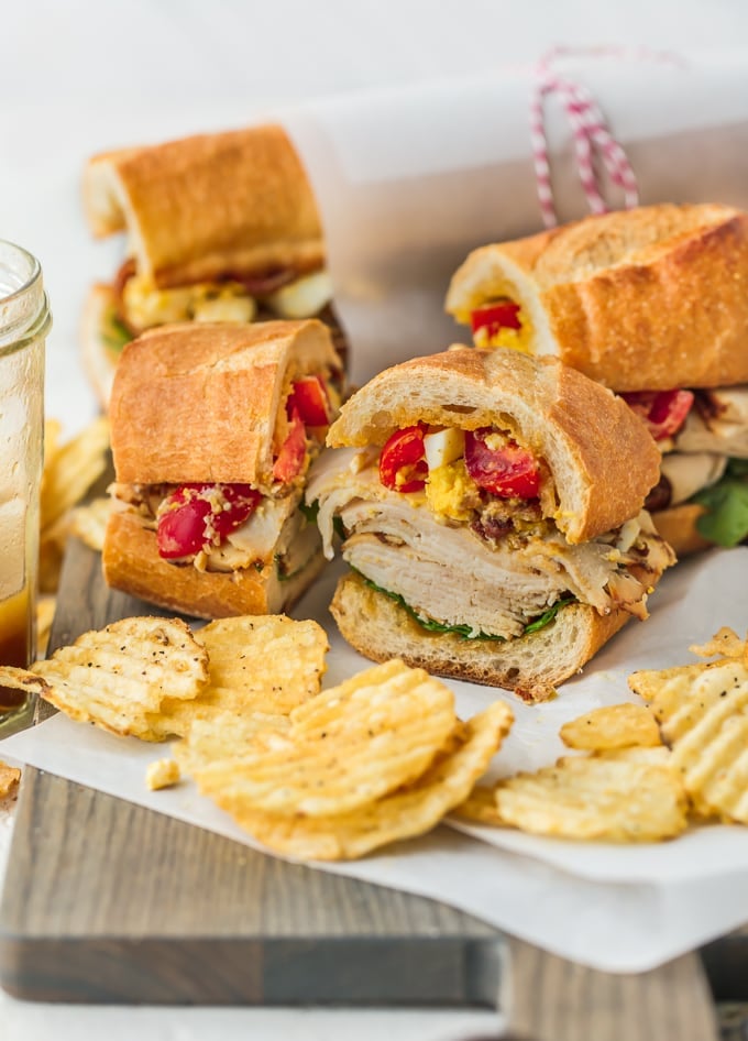 Sub sandwich sliced into small pieces, on a plate with potato chips