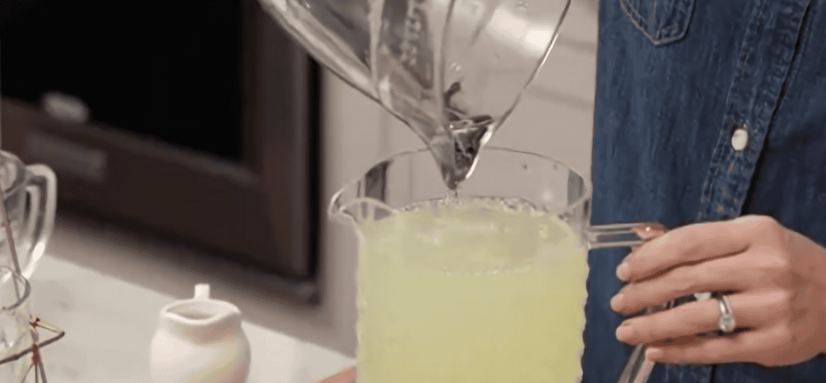 Combining lemonade ingredients in a pitcher.