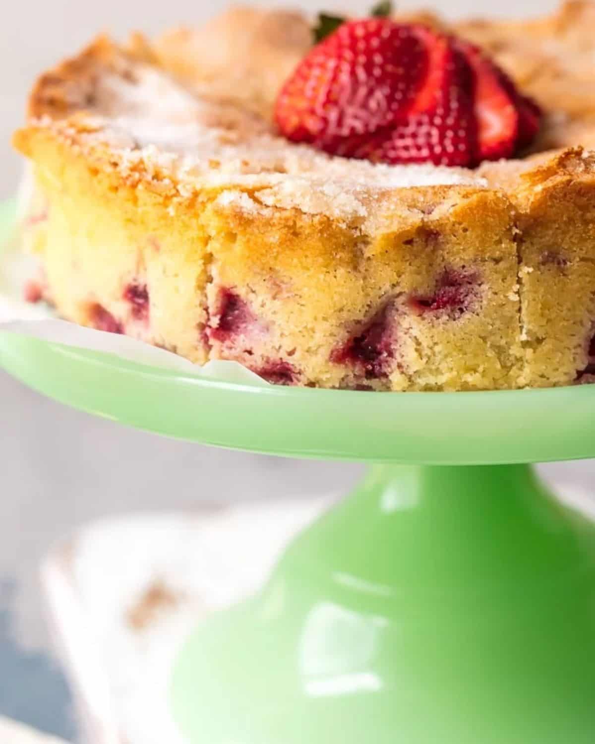 This Strawberry Buttermilk Cake is moist, soft, and so yummy! I love the light & simple flavor of this lemon strawberry cake. Strawberry buttermilk cake on a green cake stand.