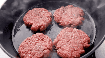 cooking 4 hamburgers in a pan.